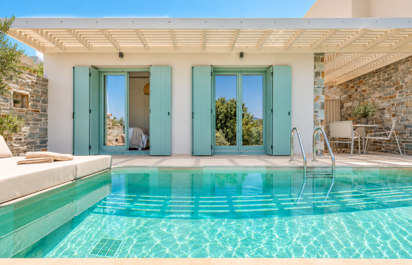 Private pool terrace at Minnŏ Boutique Hotel & Spa on Skopelos, with turquoise water, mint-green shutters, stone walls, a pergola and outdoor seating.