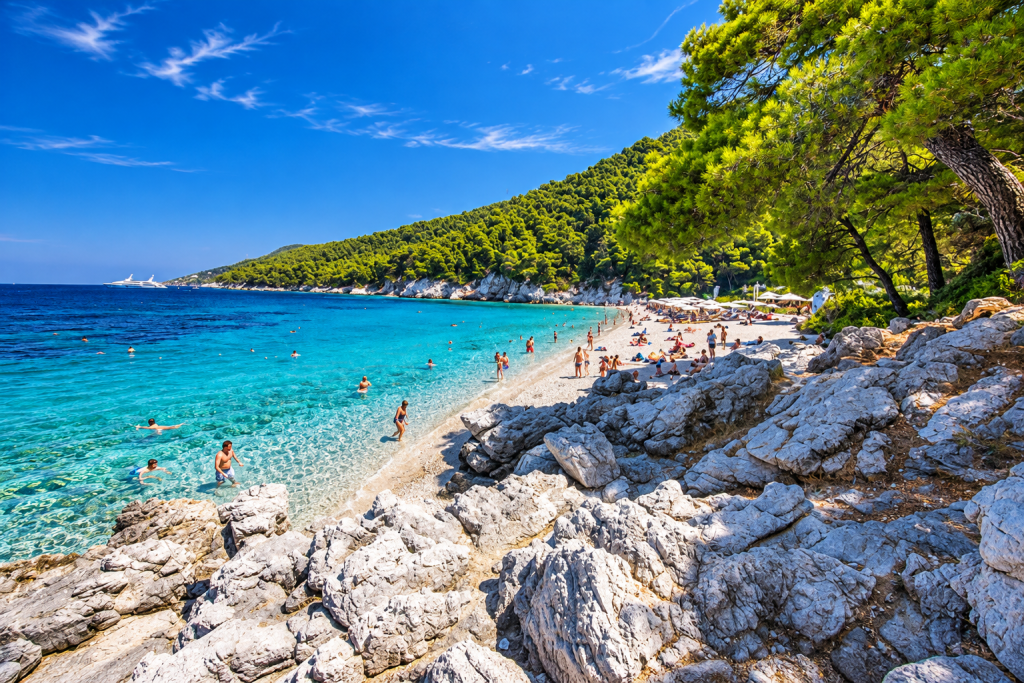 Kastani Beach on Skopelos with clear Aegean water, pine-covered hills and rocky shoreline.