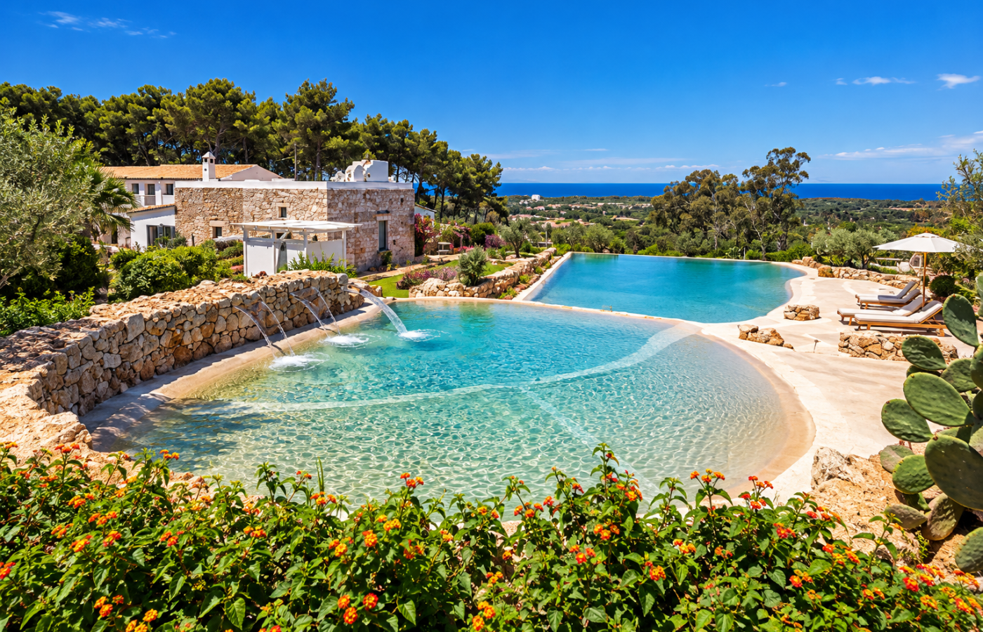 Tiered turquoise swimming pools at Masseria Fontanelle, surrounded by Mediterranean gardens, stone walls, pine trees and a distant view of the Ionian Sea.