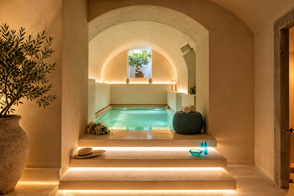 Spa plunge pool at La Fiermontina Palazzo Bozzi Corso in Lecce, set beneath arched ceilings with warm stone steps, soft lighting, rolled towels and Mediterranean décor.
