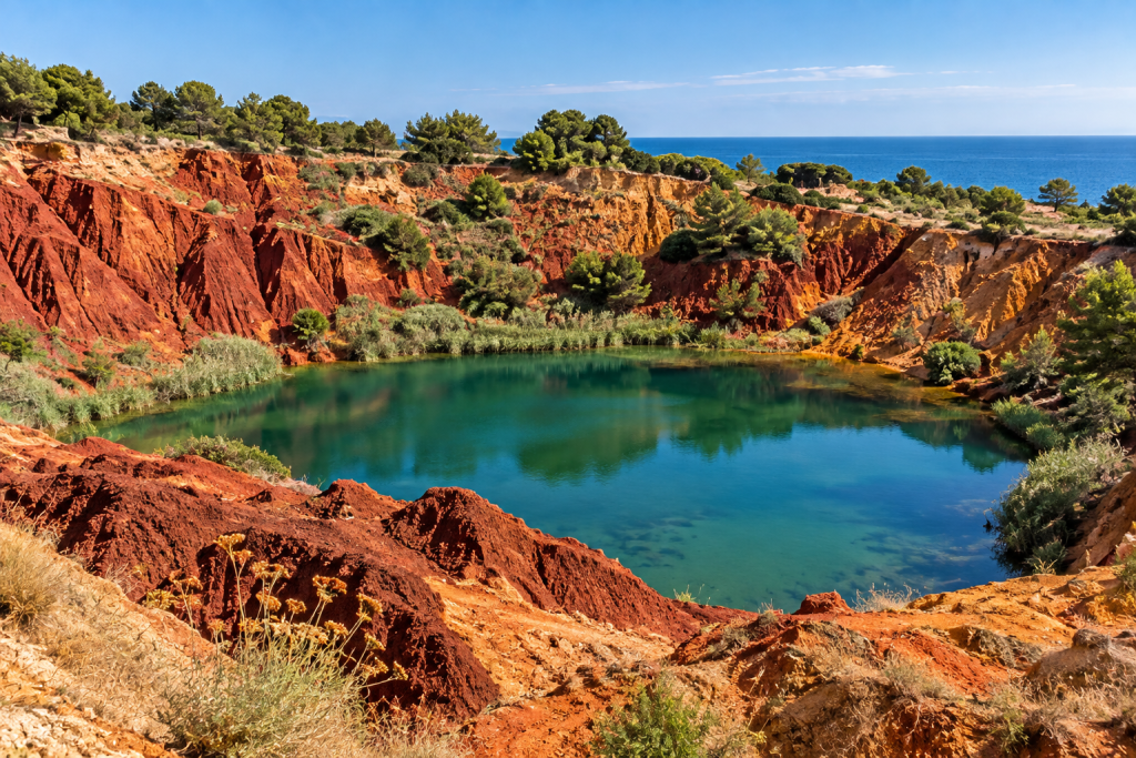 Red earth and green water at the former bauxite quarry near Otranto, Puglia.